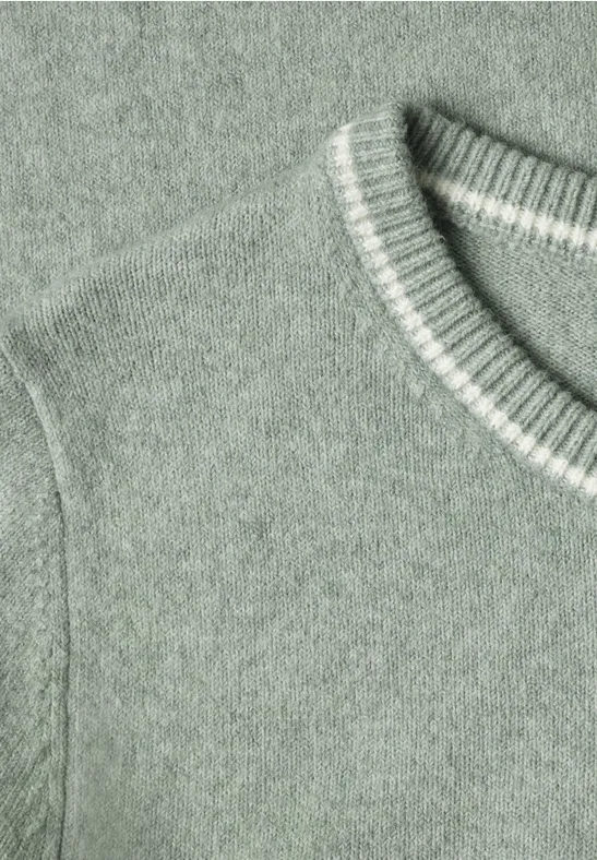 Nahaufnahme eines grünen Strickpullovers mit Rundhalsausschnitt und gerippten Bündchen.