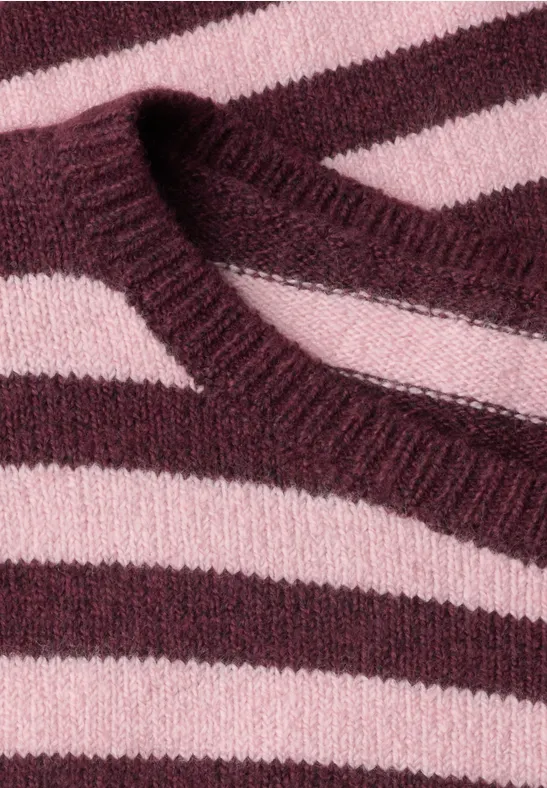 Zbliżenie na dzianinowy sweter w poziome różowe i bordowe pasy.