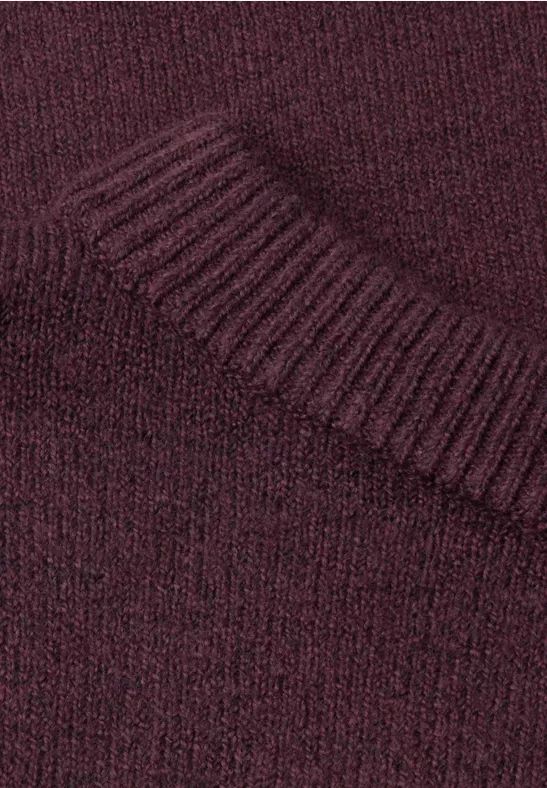 Gros plan d’un pull en maille bordeaux avec col côtelé.