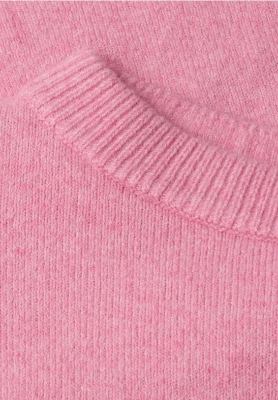 Nahaufnahme eines rosafarbenen Strickpullovers mit weicher, fein gestrickter Textur.