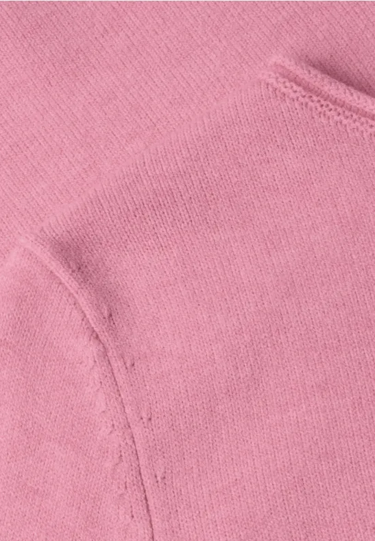 Close-up van roze sweaterstof met naad en zakdetail.