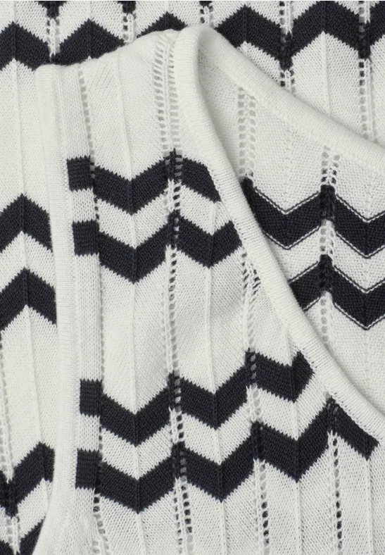 Nahaufnahme eines weißen Stricktops mit schwarzen Zickzackstreifen