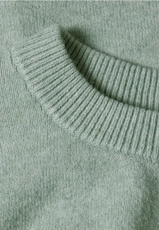 Nahaufnahme eines hellgrünen, fein gestrickten Pullovers mit Rundhalsausschnitt.