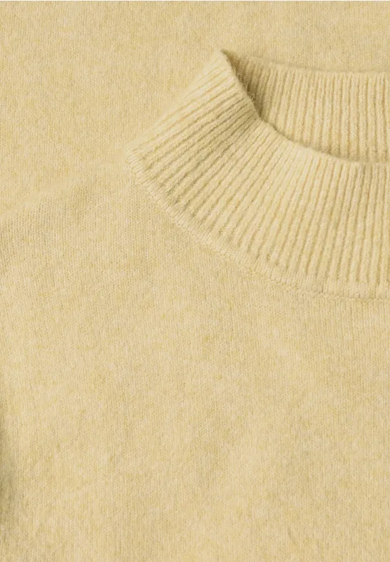 Naheaufnahme eines hellgelben Strickpullovers mit Rundhalsausschnitt.