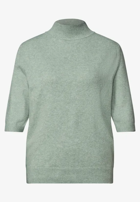 Hellgrüner Pullover mit hohem Kragen und halblangen Ärmeln.