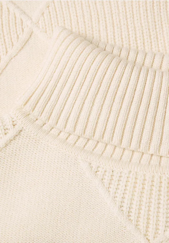 Nahaufnahme eines cremefarbenen Strickpullovers mit Rippkragen und strukturiertem Muster.