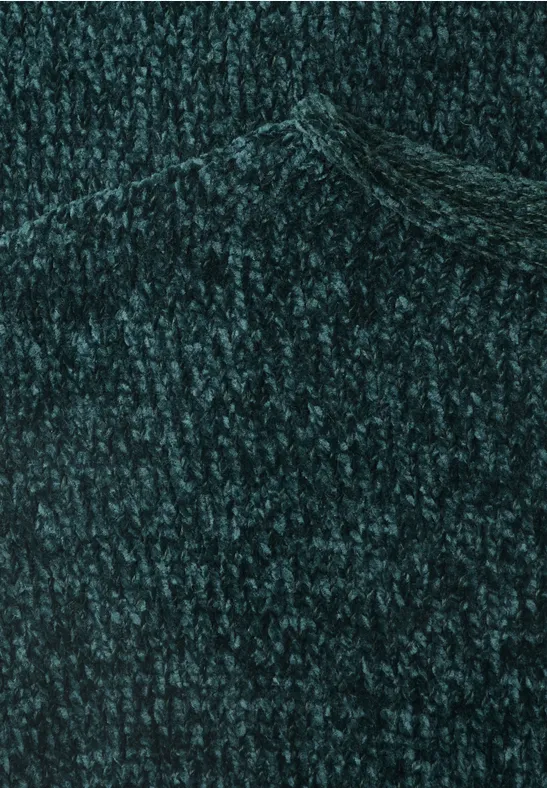 Gros plan sur un pull vert foncé tricoté grossièrement.