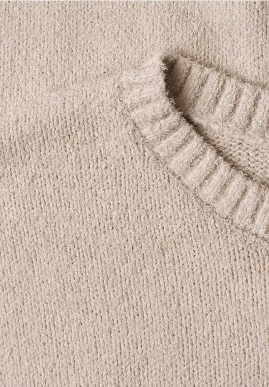Nahaufnahme eines beige gestrickten Pullovers mit geripptem Kragen