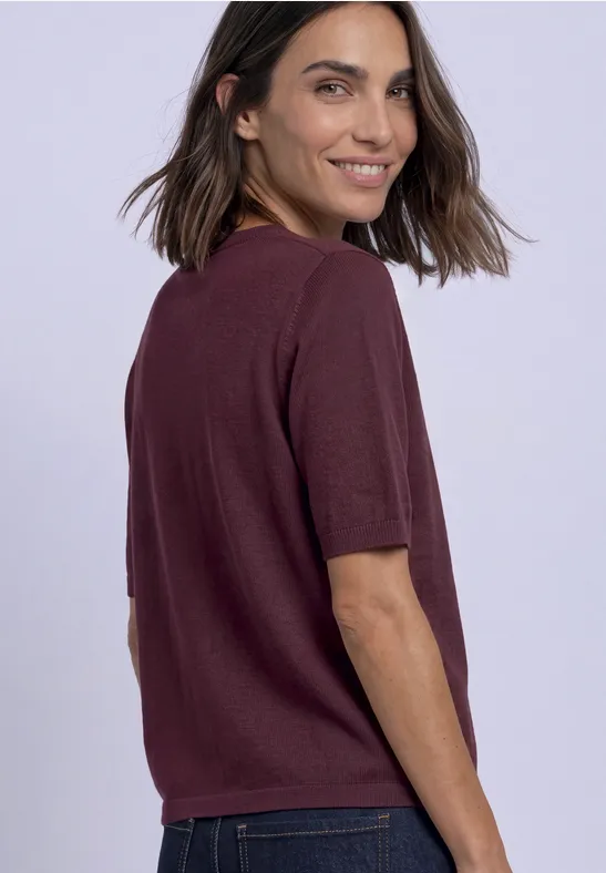 Femme en T-shirt violet souriante regardant par-dessus son épaule