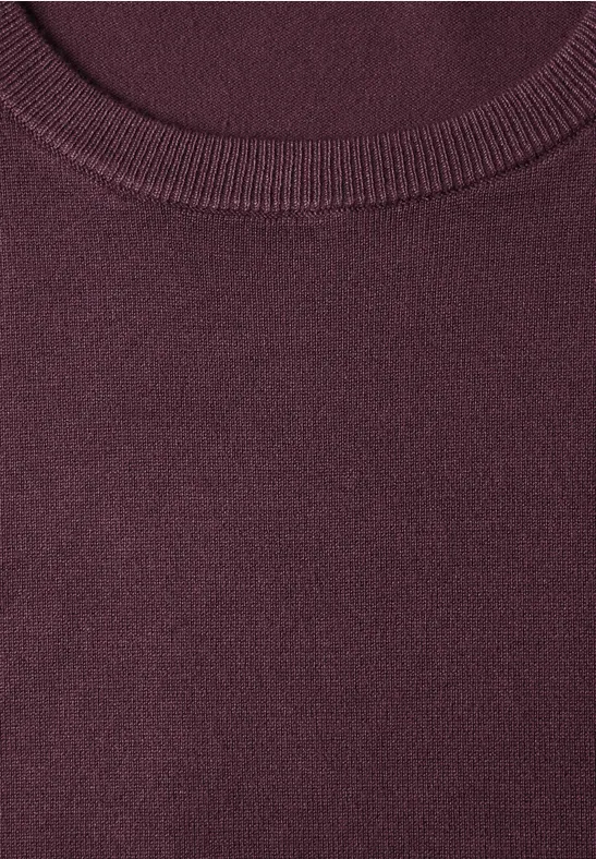 Gros plan d’une encolure ronde bordeaux d’un pull en maille.
