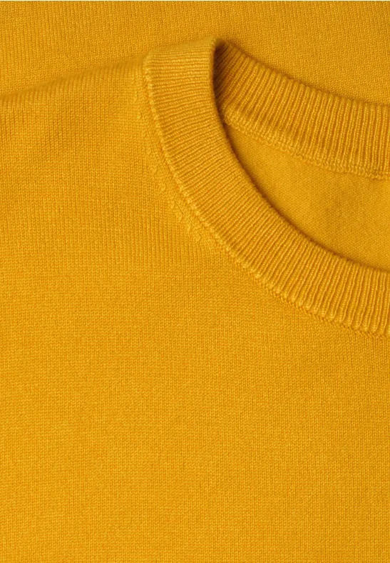 Nahaufnahme eines senfgelben Strickpullovers mit Rundhalsausschnitt.