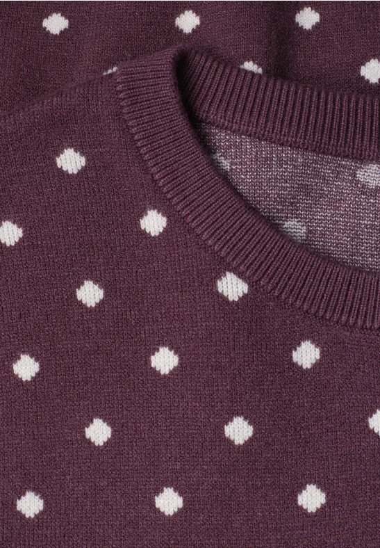 Nahaufnahme eines violetten Pullovers mit weißen Punkten.