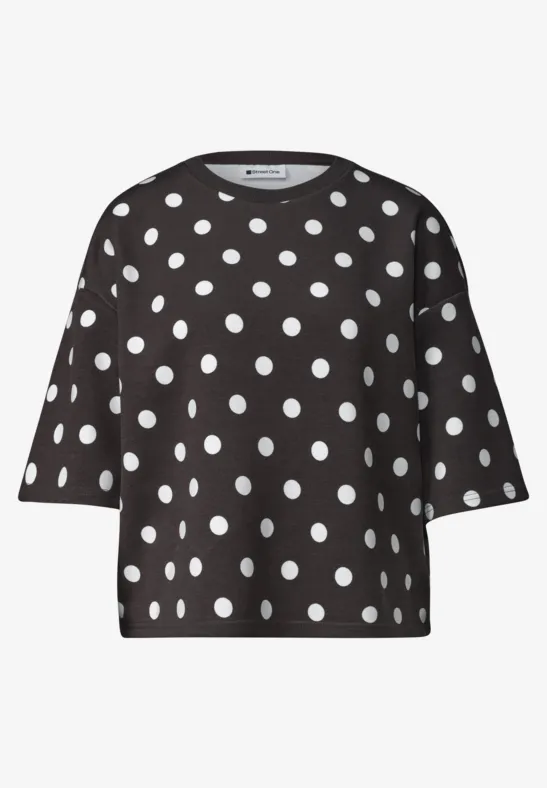 Schwarzes kurzärmeliges Oberteil mit weißen Polka-Dots.