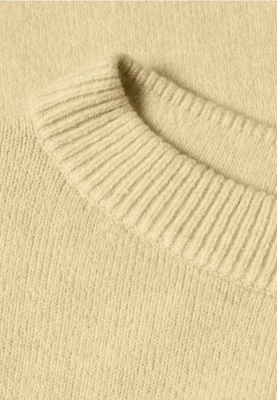 Nahaufnahme eines beigen Strickpullover-Kragens aus weicher Wolle.