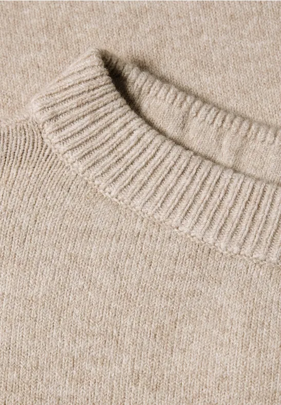 Close-up van een beige gebreide trui met geribbelde ronde hals.