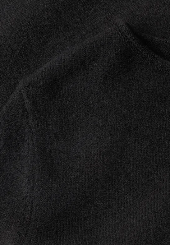 Nahaufnahme eines schwarzen Fleece-Stoffs mit sichtbarer Naht und Tasche.