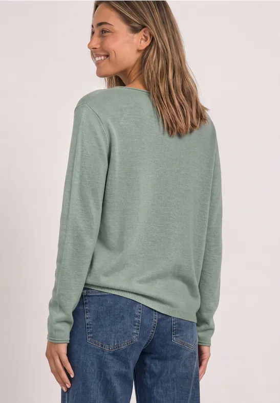Rückenansicht einer Frau in grünem Pullover und Jeans.