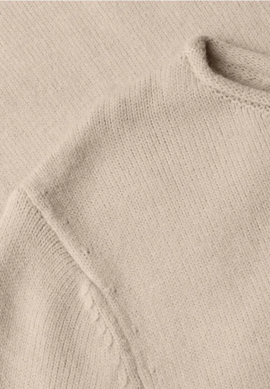 Nahaufnahme eines hellbeigen Strickpullovers mit Schulternaht