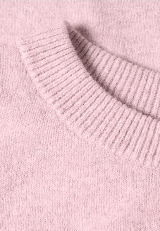 Nahaufnahme eines flauschigen, rosa Pullovers mit geripptem Kragen.