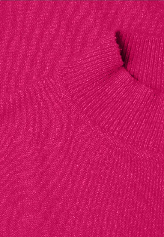 Nahaufnahme eines pinkfarbenen Strickpullovers mit geripptem Kragen und Ärmelbündchen.