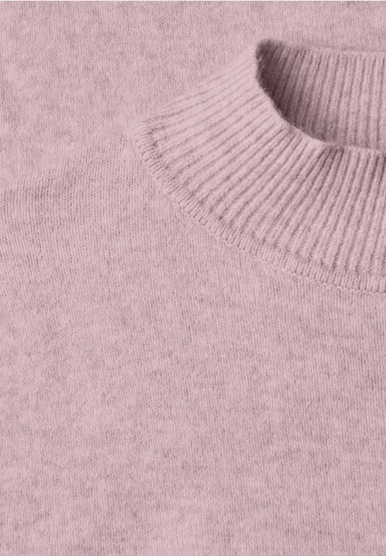 Nahaufnahme eines altrosa Strickpullovers mit geripptem Kragen.