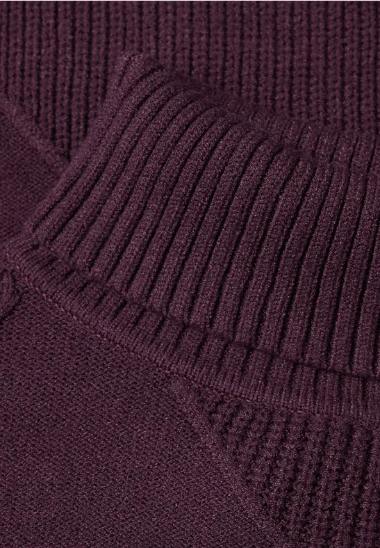 Nahaufnahme eines dunkelvioletten Strickpullovers mit geripptem Rollkragen