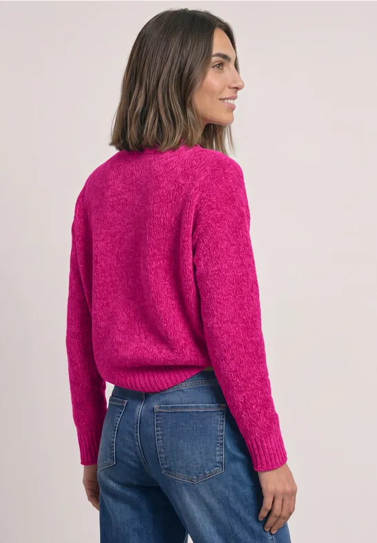Frau in pinkem Pullover und blauer Jeans, von der Seite und von hinten zu sehen.