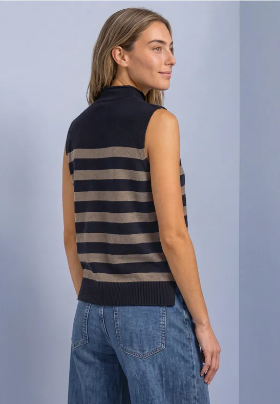 Rückansicht einer Frau, die eine ärmellose, gestreifte Strickweste mit Stehkragen und Jeans trägt.