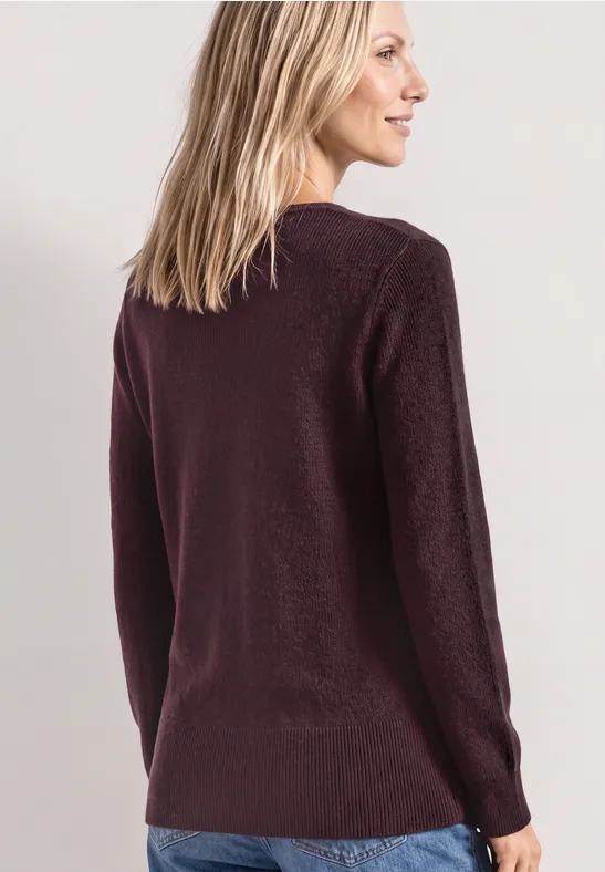 Femme de dos en pull violet et jean, regard tourné légèrement sur la droite.