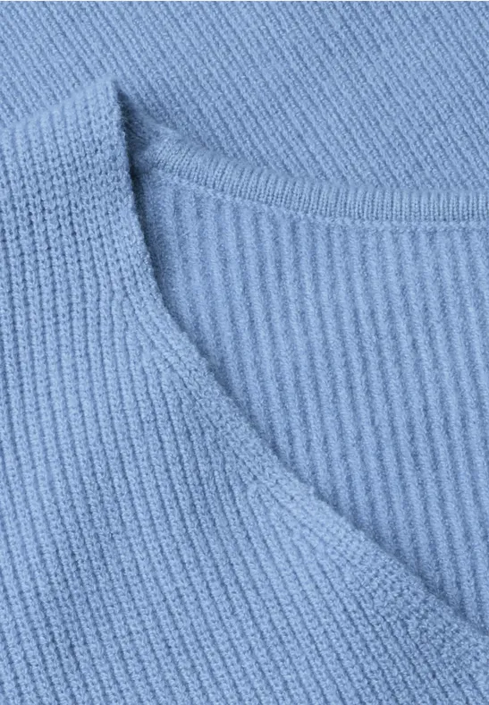 Nahaufnahme eines hellblauen, gerippten Strickpullovers mit V-Ausschnitt.