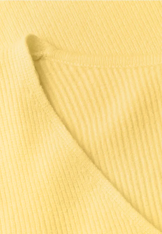 Nahaufnahme eines gelben, gerippten Strickstoffs mit Rundhalsausschnitt