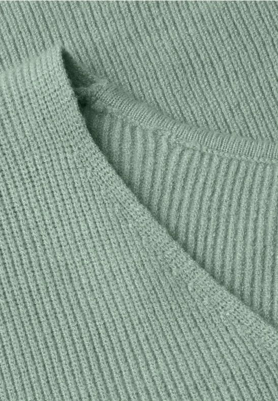 Nahaufnahme eines hellgrünen, gerippten Strickpullovers mit V-Ausschnitt.