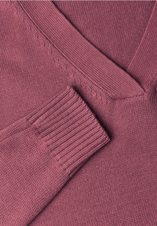 Detailaufnahme eines dunkelroten Strickpullovers mit V-Ausschnitt und Rippbündchen am Ärmel.