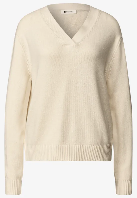 Beiger Strickpullover mit V-Ausschnitt, langen Ärmeln und Rippbündchen an Saum und Ärmeln.