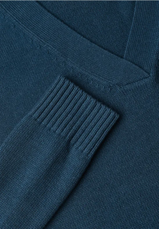 Nahaufnahme eines dunkelblauen Strickpullovers mit V-Ausschnitt und Rippbündchen am Ärmel.
