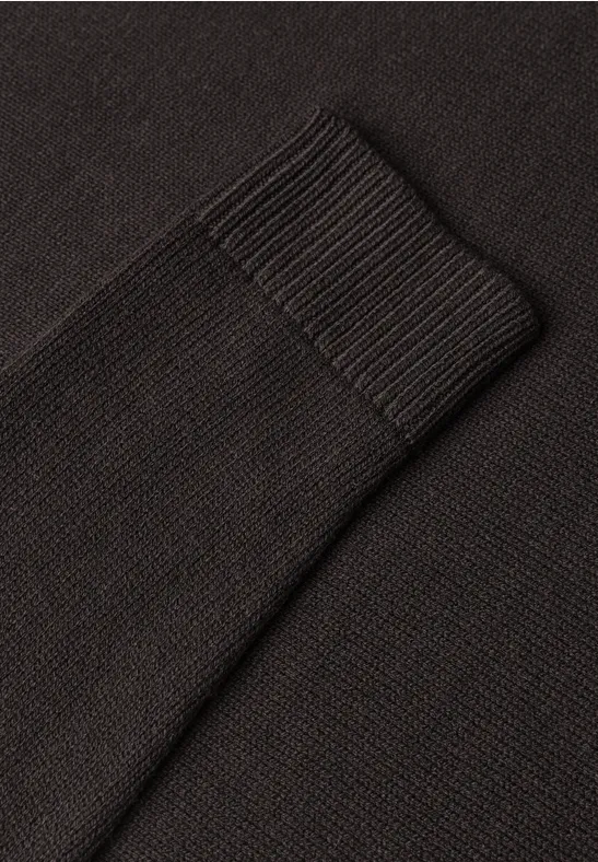 Nahaufnahme eines schwarzen Strickpullover-Ärmelbündchens mit geripptem Stoff.