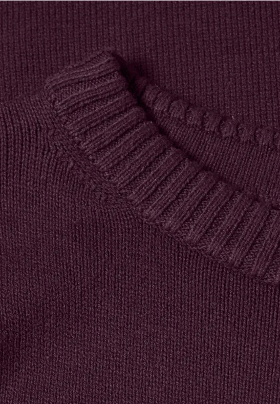 Nahaufnahme eines weinroten Strickpullovers mit Rundausschnitt und geripptem Kragen.
