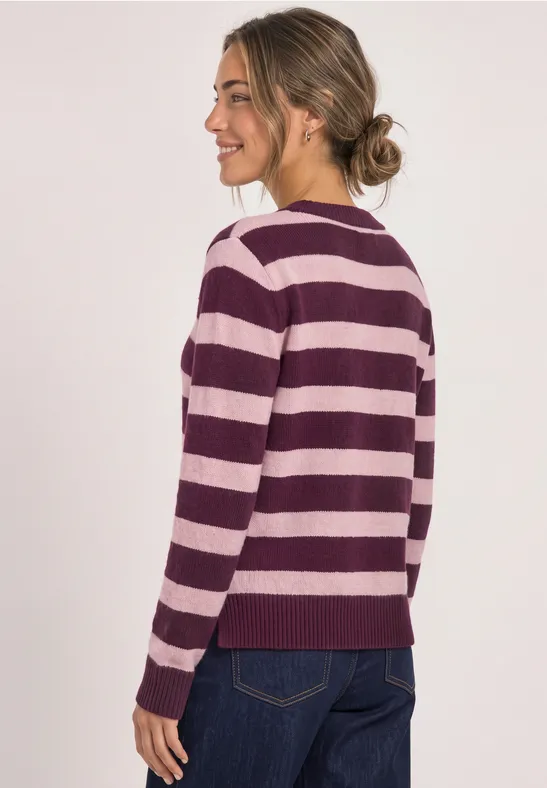 Frau in pastell-lila-rosa gestreiftem Pullover und Jeans, von hinten mit lockerem Dutt.
