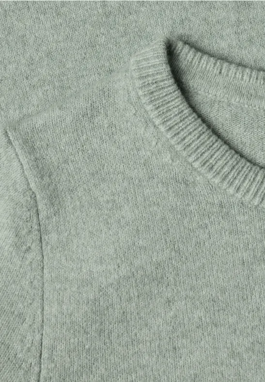 Nahaufnahme eines hellgrau-grünen Strickpullovers mit Rundhalsausschnitt und Schulteransatz.