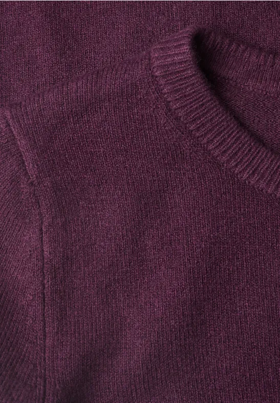 Nahaufnahme eines weichen, lila Strickpullovers mit feiner Maschenstruktur.