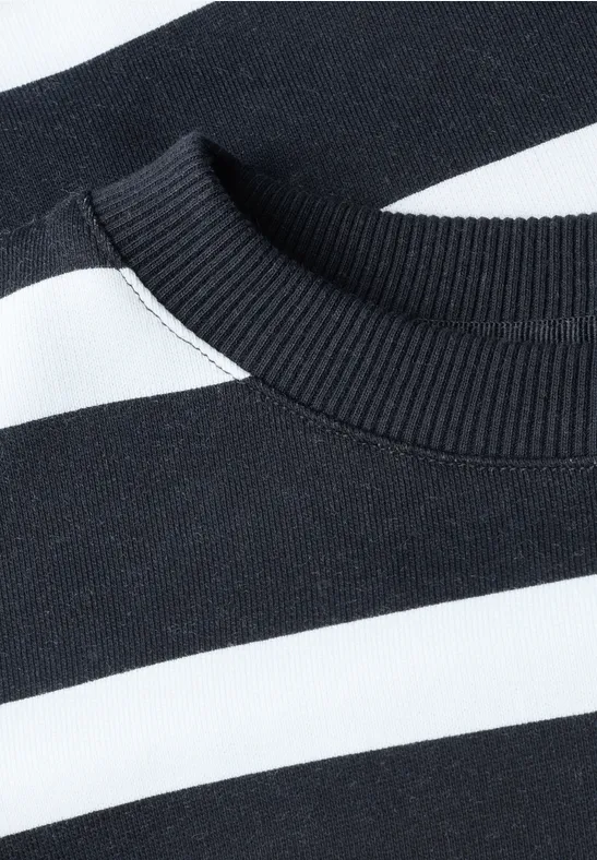 Detailfoto van de halslijn van een zwart-wit gestreepte trui met ronde hals.