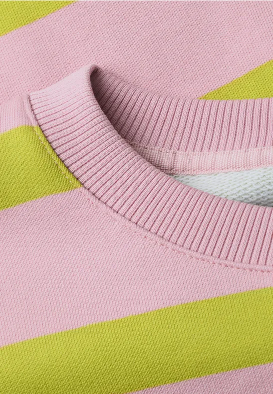 Nahaufnahme eines Rundhalsausschnitts eines Pullovers mit breiten rosa und limettengrünen Streifen.