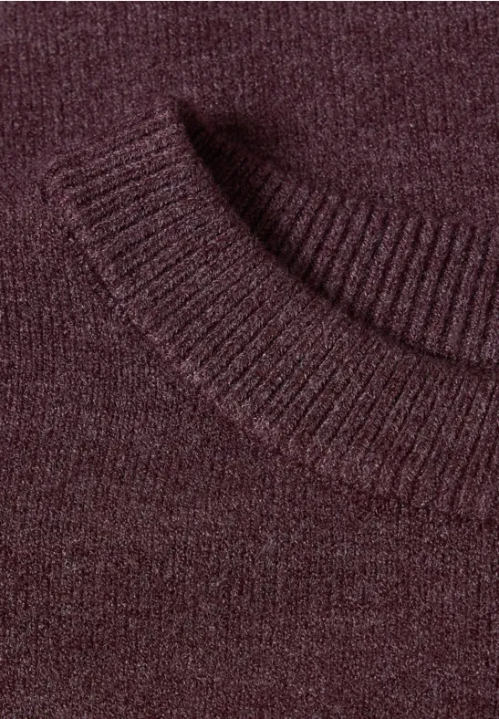 Nahaufnahme eines burgunderroten Strickpullovers mit geripptem Kragen.