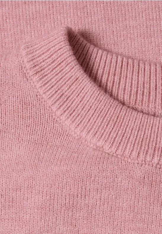 Nahaufnahme eines rosa gestrickten Pulloverkragens mit feinem Strukturmuster.