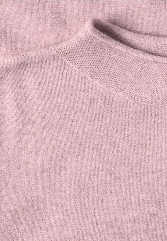 Nahaufnahme eines rosafarbenen Strickpullovers mit feiner Textur und Rippenstrick am Kragen.