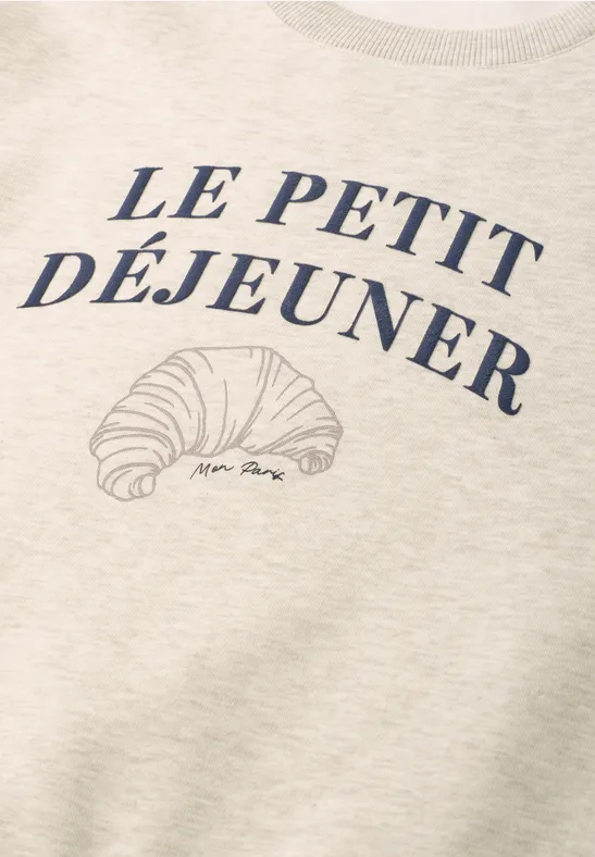 Beżowy t-shirt z napisem 'Le Petit Déjeuner' i szkicem rogalika.
