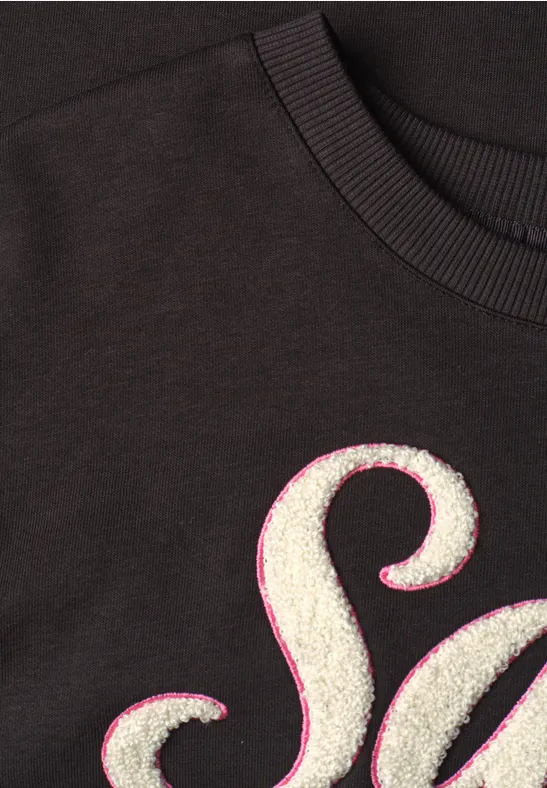 Czarny t-shirt z białą, puszystą literą 'S' obramowaną różową linią