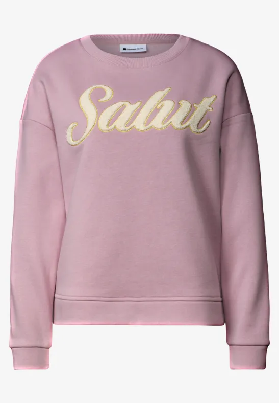 Rosa Sweatshirt mit gelbem Schriftzug „Salut“ in verspielter Schrift.