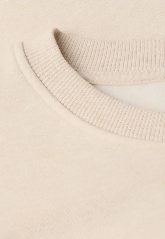 Nahaufnahme eines beigen T-Shirt-Kragens mit feiner Rippstruktur