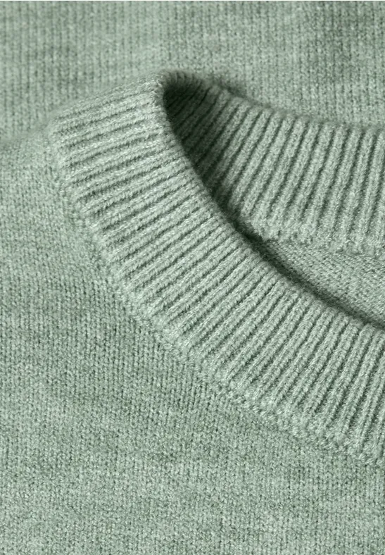 Nahaufnahme eines mintgrünen Strickpullovers mit geripptem Rundhalsausschnitt.
